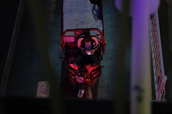 一位男士骑着红色摩托车在一位女士旁边沿着街道行驶