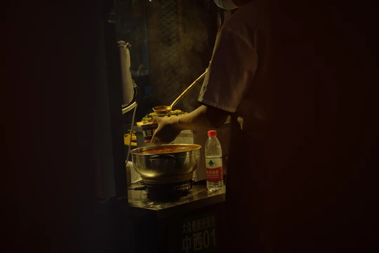 一个站在黑暗房间里的男人在炉子上烹饪食物