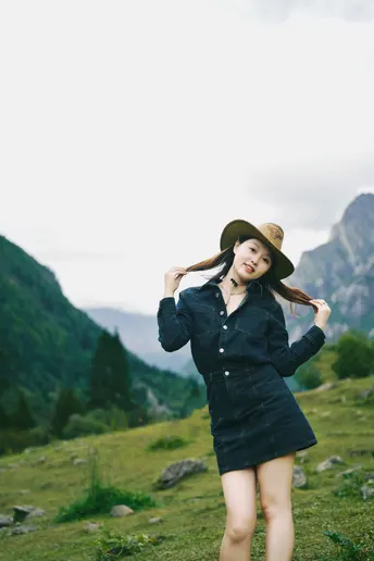 一位长发女子穿着黑色连衣裙和帽子站在田野中
