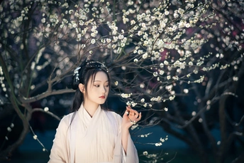 一位穿着和服的女子站在盛开的花树前