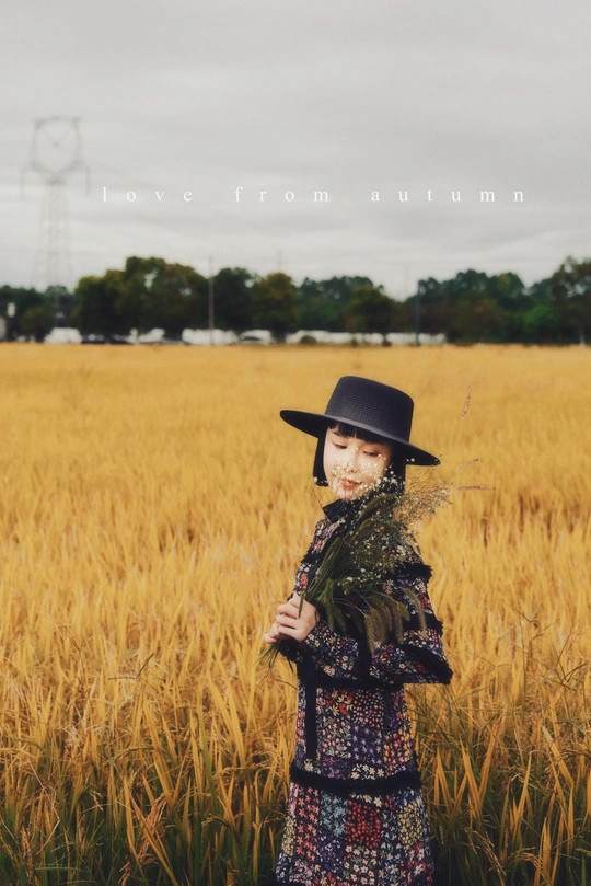 一个戴黑色帽子站在麦田里的女人