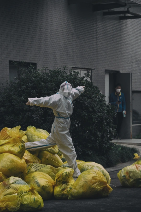 穿着防护服的人在建筑物前拿着装满东西的包。