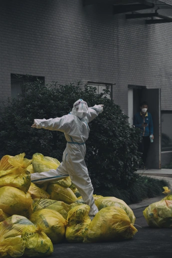 穿着防护服的人在建筑物前拿着装满东西的包。