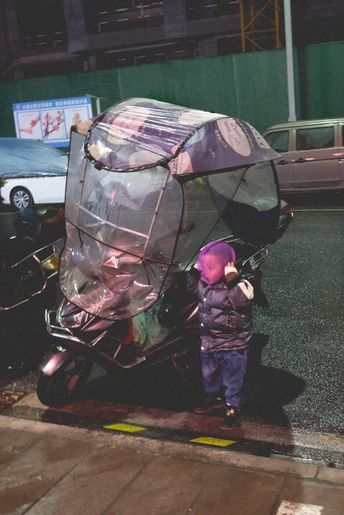 站在街边 旁边是停着一辆摩托车的街道上 有一个小男孩站在一个男子旁边。