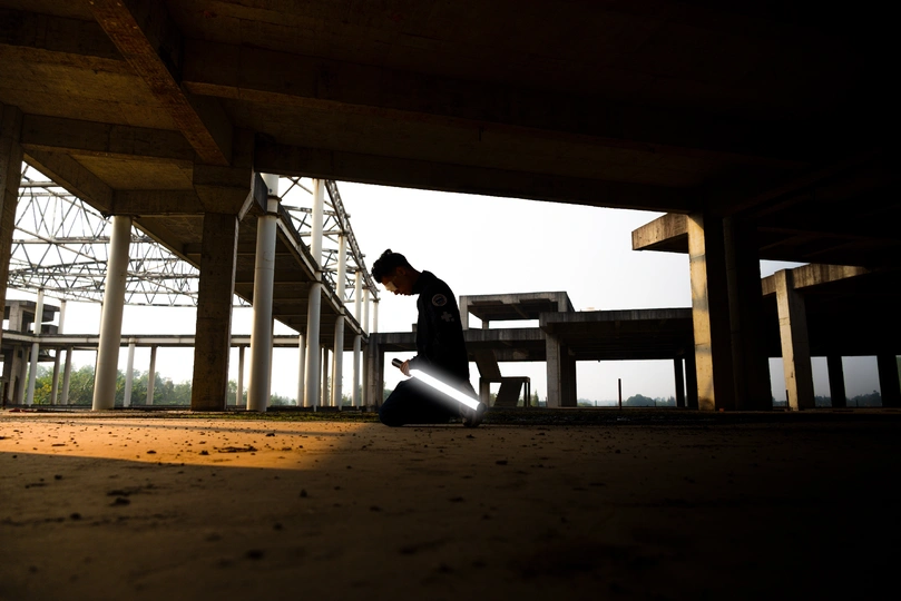 一个人在桥下建筑物的地板上读书 手里拿着手电筒。