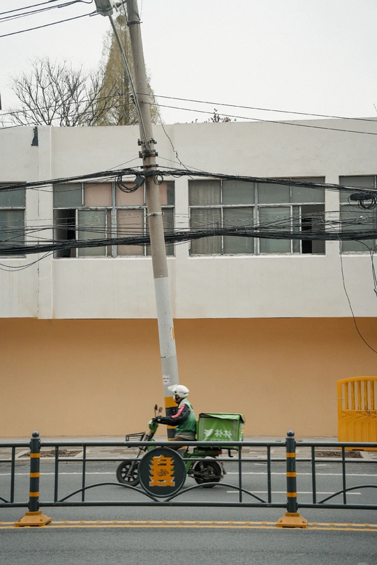 一名男子在街边的一根杆子上操作起重机 靠近一座建筑。