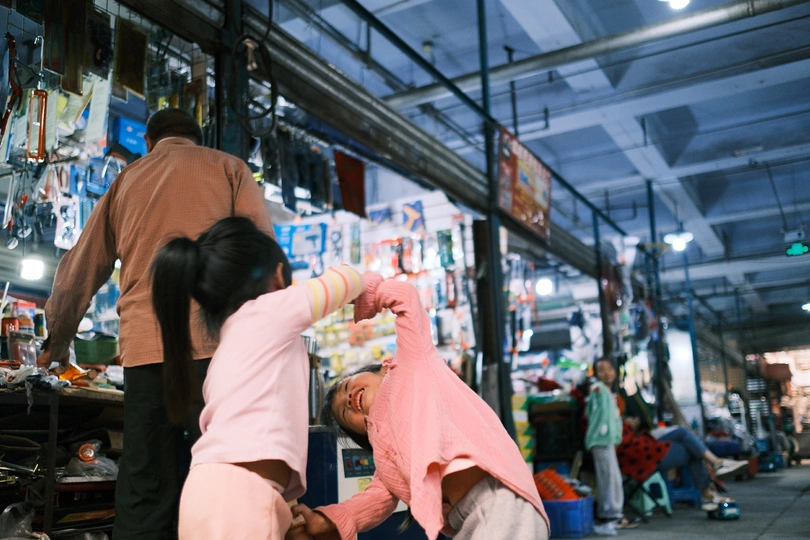 市场里有个女人抱着个小孩子 背景有人在玩耍