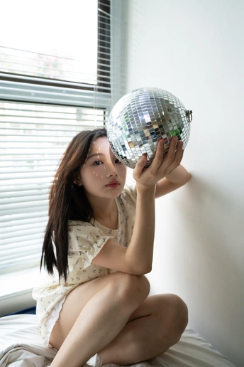 一个年轻女子坐在床上手里拿着一个球