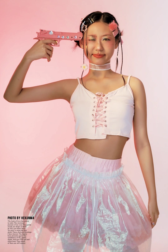 一位身穿粉色裙子的年轻女子在杂志上持枪摆姿势