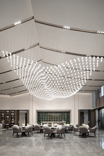 建筑或图书馆的大厅 配有桌子、椅子以及从天花板挂下的大型吊灯。