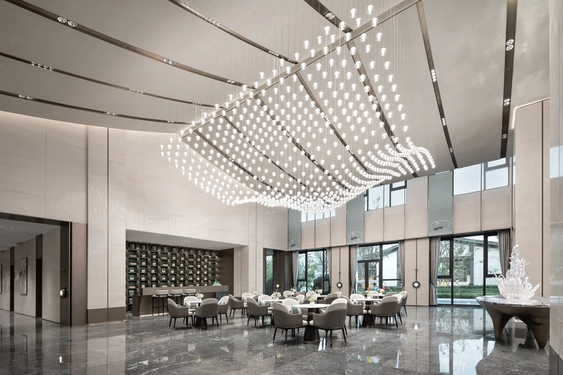 一个现代化的建筑的大厅 有桌子、椅子 以及从天花板挂下的大型吊灯。