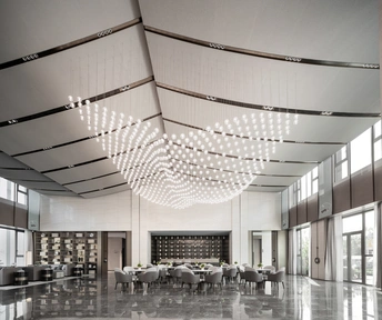 一个大型建筑物的大厅 有桌子、椅子 以及从天花板挂下的吊灯。