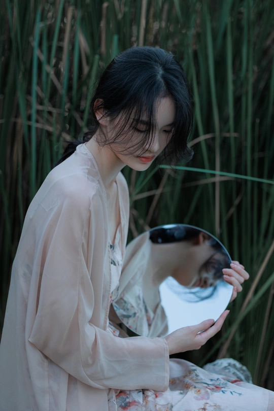 一个穿着和服的年轻女子拿着镜子看着自己