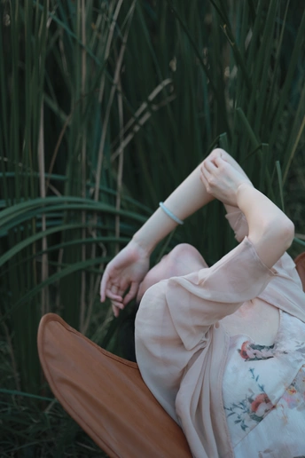 一个穿着连衣裙、戴着帽子的女人坐在草地上的椅子上