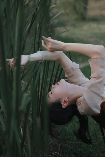 一位年轻女子在高高的草地前摆姿势