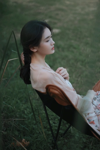 一位年轻女子坐在草地上的椅子上