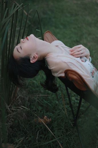 躺在草地上的椅子上的年轻女子
