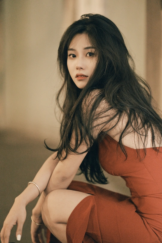 一个穿着红裙子的年轻女子坐在一个手提箱旁边的一个过道里