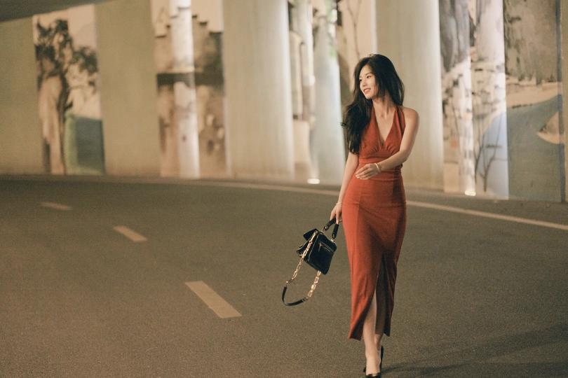 一个穿着红裙子的女人走在一条空荡荡的街道上