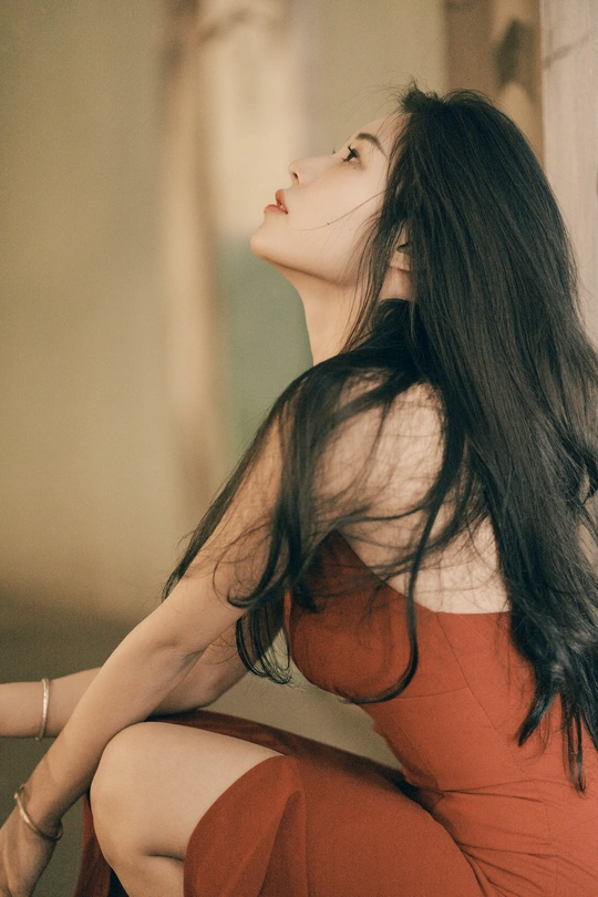 一个穿着红裙子的年轻女子坐在走廊地板上