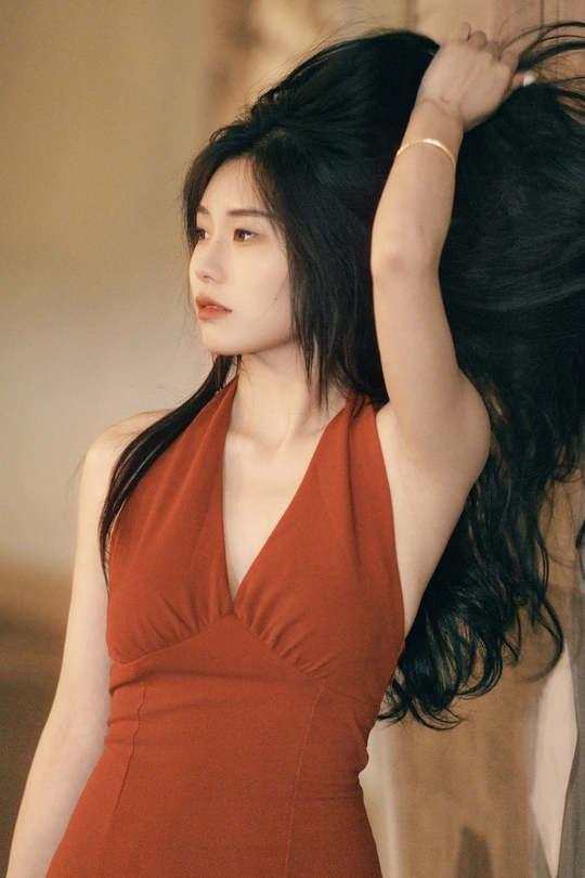 一位穿着红色连衣裙的年轻女子 长发披在头顶上 正在摆姿势。