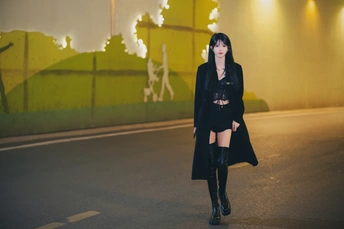 一个穿着黑色外套的年轻女子在夜晚走街