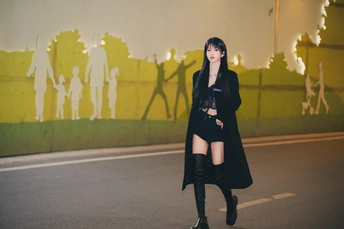 一个穿着黑色外套和靴子的年轻女子正在街上走