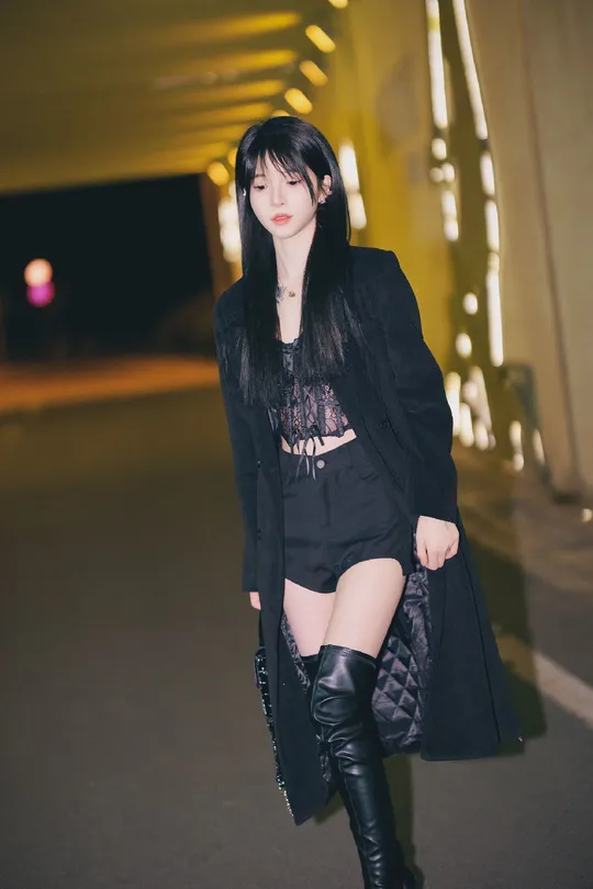 一位穿着黑色外套和高筒靴子的女孩在街上。