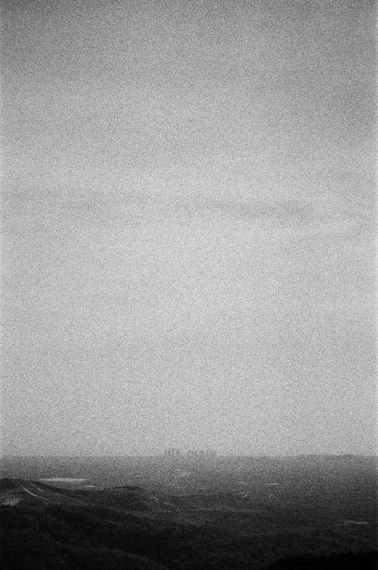 一张黑白照片 一只风筝在田野上方的天空中飞翔。