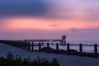 日落时 海洋上空的粉红色和紫色天空 有码头和灯塔