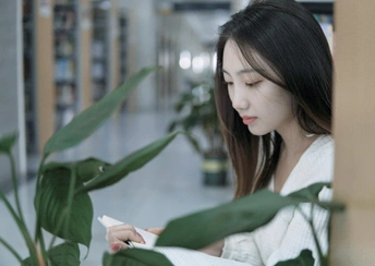 在图书馆里 一个拿着白皮书的年轻女子看着她的手机