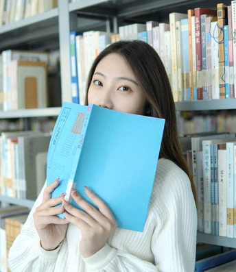 一个年轻的女人把一本蓝色的书放在脸前