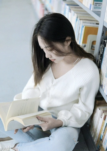 一位年轻女子坐在书架前的地板上看书