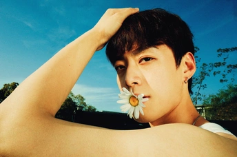 一个年轻人嘴里叼着一朵白花 一只手放在耳朵上