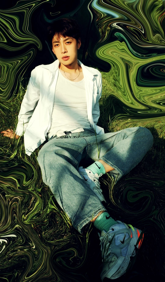 一个小男孩坐在绿色的草地上 在绿色的水面前