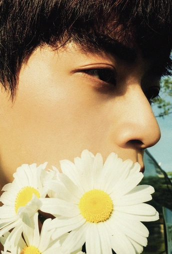 一个满头白发的年轻女孩把一朵白花捧在脸上