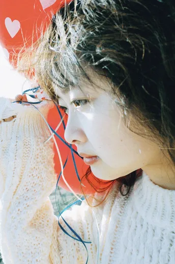 一位戴着耳机看红色气球的年轻女子