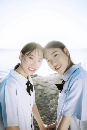 一些穿着校服的年轻女孩在海滩上牵手拍照