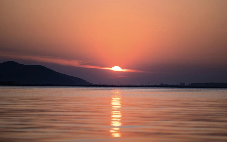夕阳西下 背景是山脉 水体在前景中。
