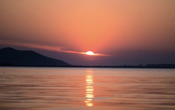 夕阳西下 背景是山脉 水体在前景中。