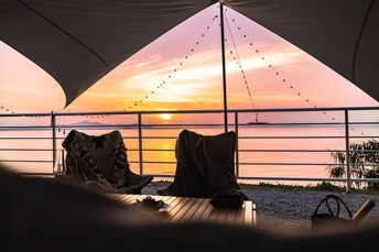 一个人在日落时分坐在甲板上的桌子旁 俯瞰海洋