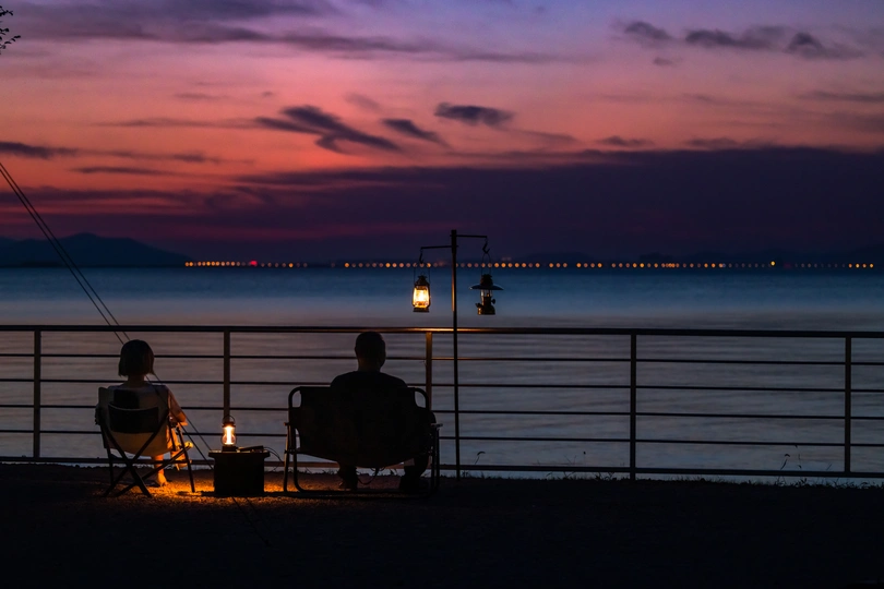 一些人在夜晚坐在俯瞰湖泊的椅子上