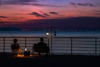 一些人在夜晚坐在俯瞰湖泊的椅子上