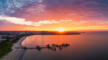 美丽的日落或日出在一片水域上 远处是一座城市 前景是海滩