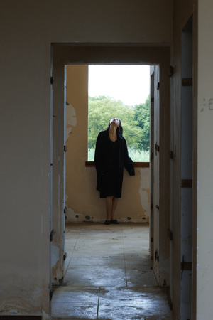 一个人穿着外套站在一条走廊里 正看着一扇建筑的敞开大门。