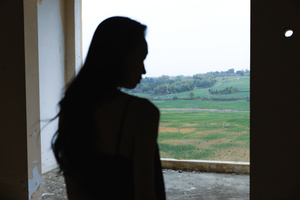 一位女性站在房间里 凝视着田野的轮廓