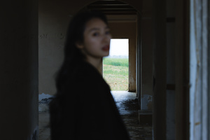 一个黑暗的走廊 有人从门中走过 一个女孩站在建筑物的走廊里。