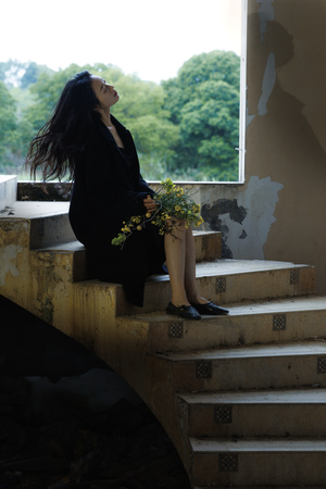 一个年轻女子坐在一些楼梯上 楼梯上有植物和鲜花。