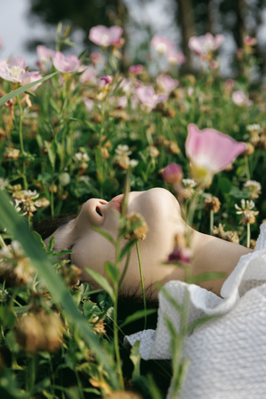 一位年轻女子躺在花丛和草地上