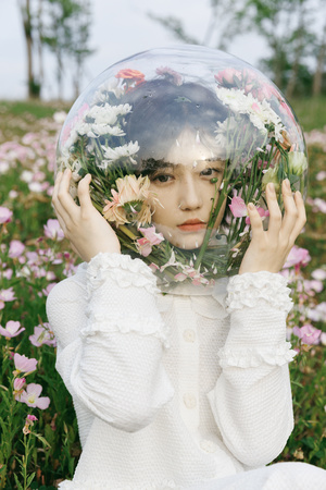 一位年轻女子在一个花丛中抱着自己的脸